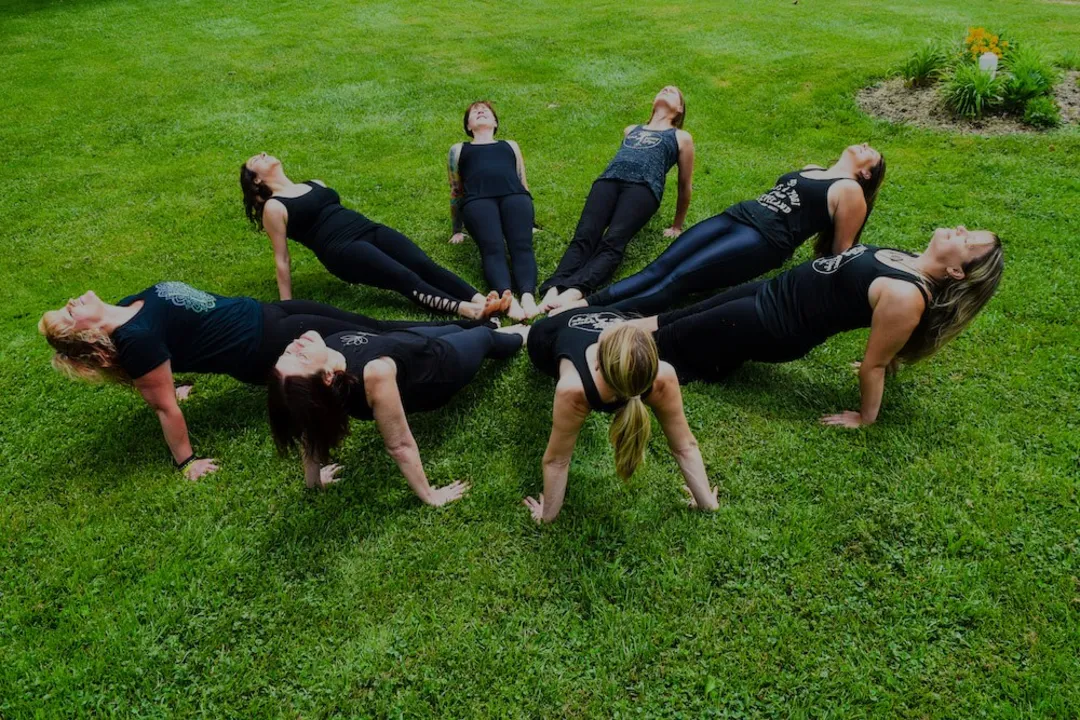 Eight Taproot teachers on the lawn, arcing into reverse plank in a circle