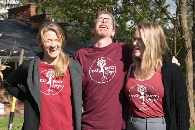 Freia, David, and Anya Ramsey laughing together in matching Taproot Yoga shirts