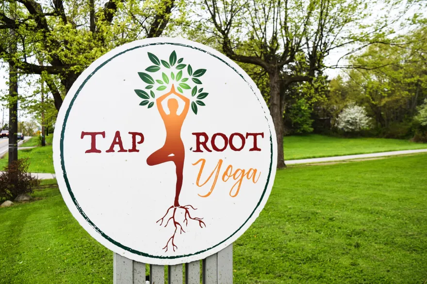 The round Taproot Yoga sign standing among spring trees